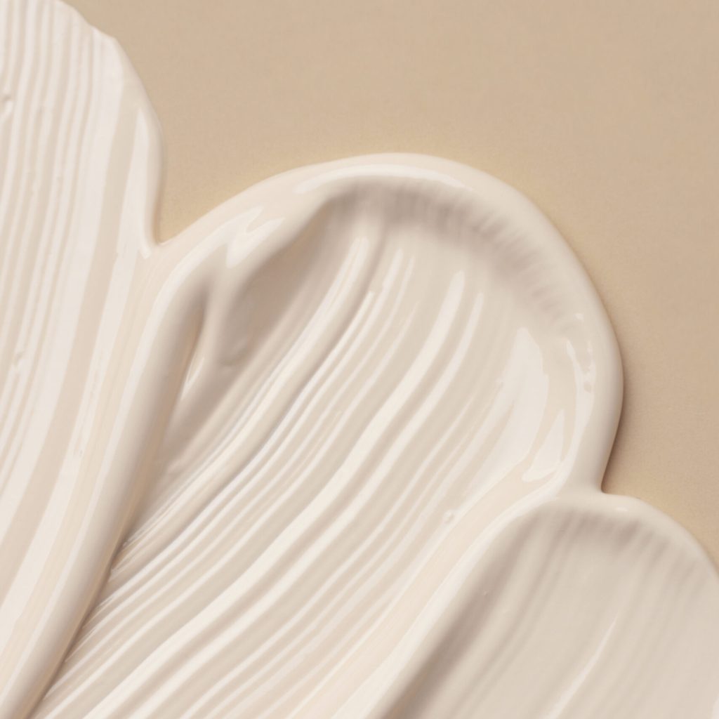 Texture cremosa di una Crema Viso Dieci in Uno, simbolo di una formulazione skincare multifunzione dalla consistenza morbida e uniforme.